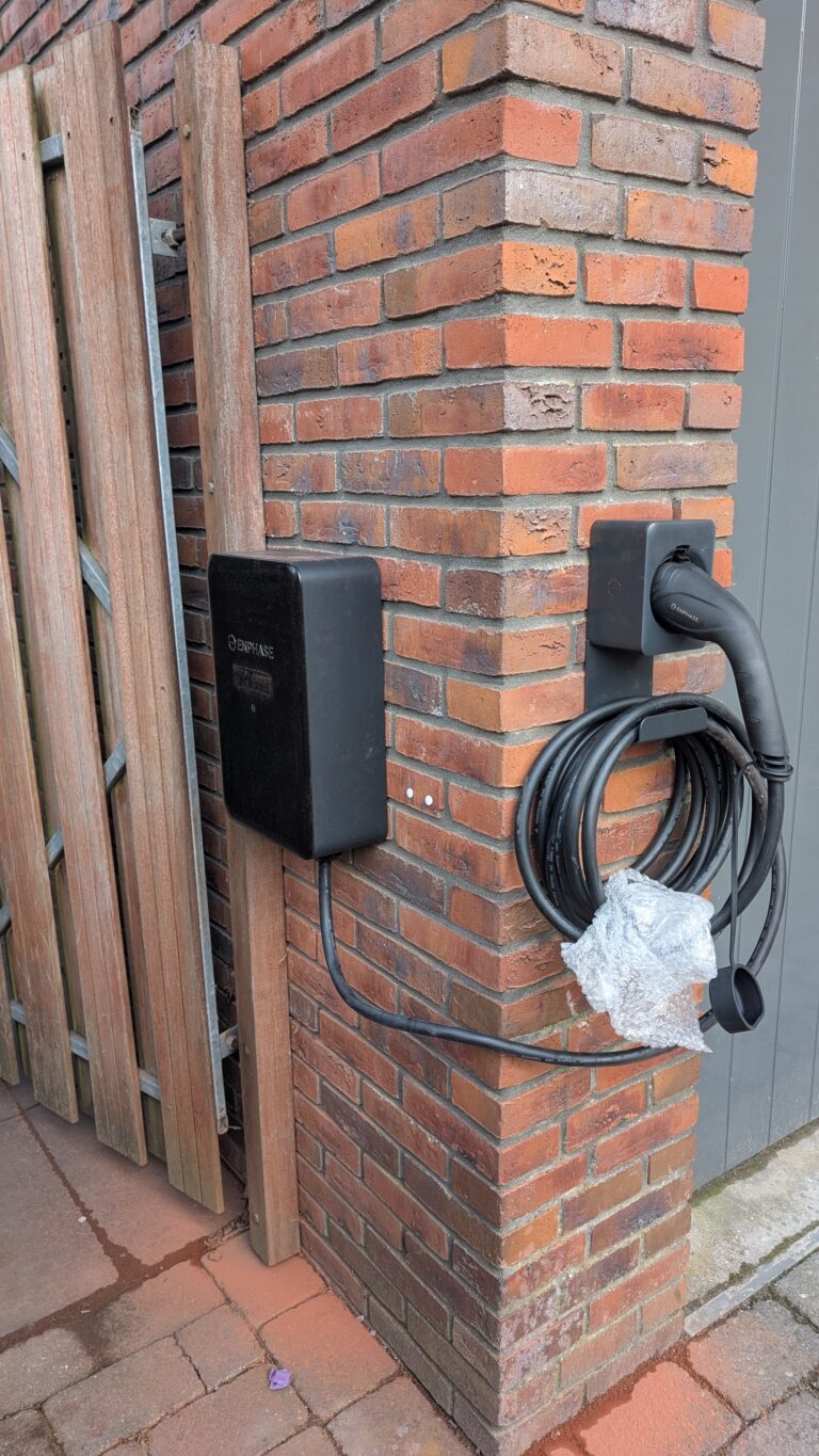 De Enphase EV lader is tegen de zijmuur van de garage gemonteerd. Naast de garagedeuren is de meegeleverd houder voor de type 2 steker en 7,5 m kabel gemonteerd.